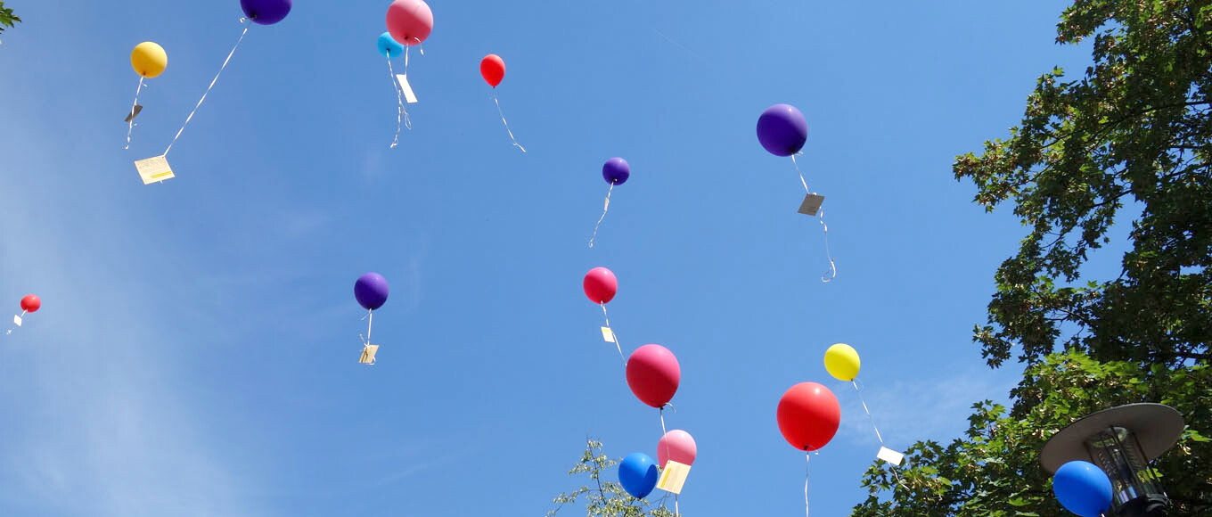 Bunte Luftballons steigen empor zum blauen Himmel